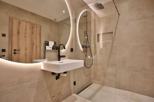 a bathroom with a sink and a shower at Das Goldjuwel - Luxury Apartments with private Spa in Goldegg