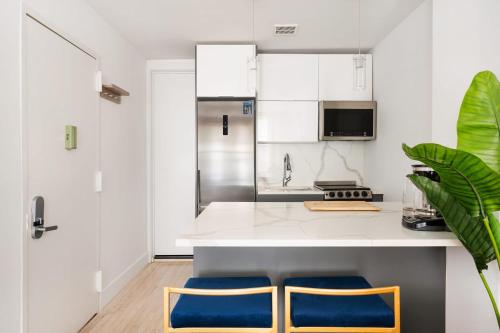 a kitchen with white cabinets and blue stools at 1597-7 Luxury Upper East Studio W&D in unit in New York