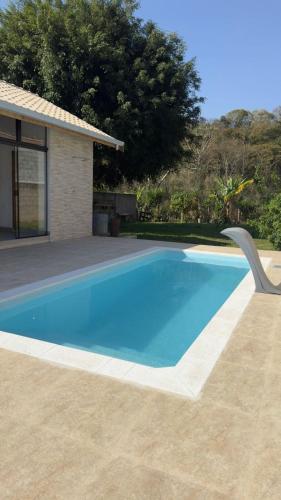 a large blue swimming pool next to a house at Chalé Beija Flor com piscina em Sapucaí-Mirim in Sapucaí-Mirim