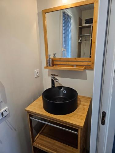 une salle de bain avec un lavabo noir et un miroir dans l'établissement L'Escale d'Héol, à Saint-Gildas-de-Rhuys
