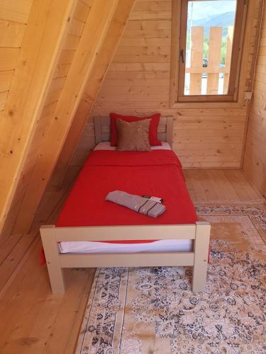 a bed in a log cabin with a red blanket at PROKLETIJE COTAGESEe in Plav