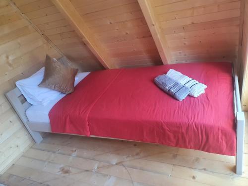 a bed in a room with a red blanket and pillows at PROKLETIJE COTAGESEe in Plav