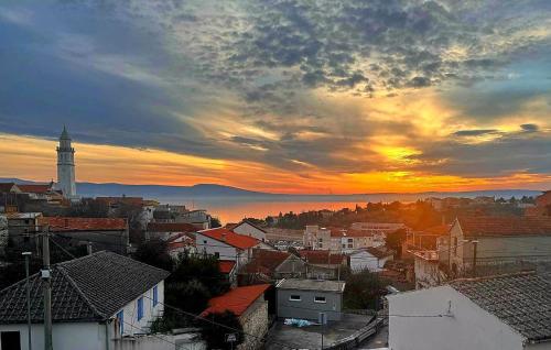 a sunset over a city with a clock tower at Beautiful Home In Novi Vinodolski in Novi Vinodolski