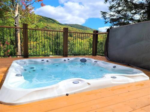 a hot tub on a deck with a fence at Nature's Luxe Retreat - Panache 638 in Mont-Tremblant