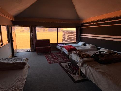 a room with four beds and a chair and windows at Milky Way Wadi Rum in Wadi Rum