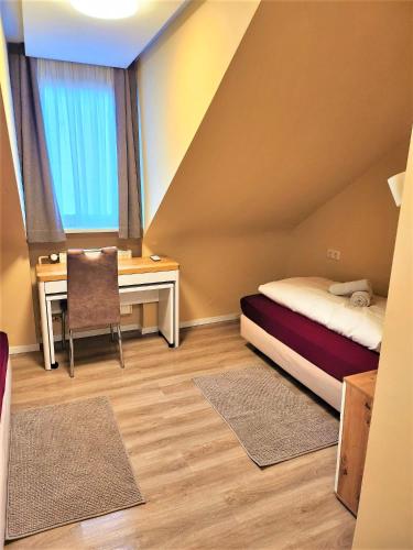 a small room with a desk and a bed and a table at Hotel Schweizer Stubb in Kaiserslautern