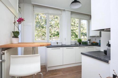 a kitchen with white cabinets and a table and two windows at Beautiful quiet Apt in the center of Amsterdam in Amsterdam