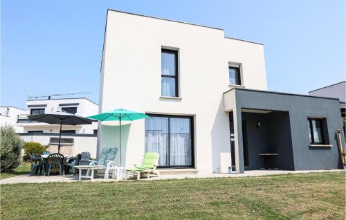 a white house with chairs and umbrellas in a yard at Nice Home In Clohars-Carnoët With Wifi in Clohars-Carnoët