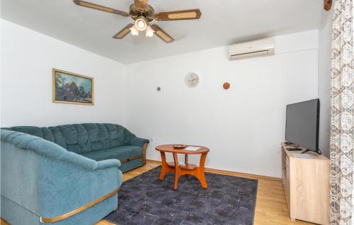 a living room with a blue couch and a ceiling fan at Nice Apartment In Krk With Wifi in Brzac