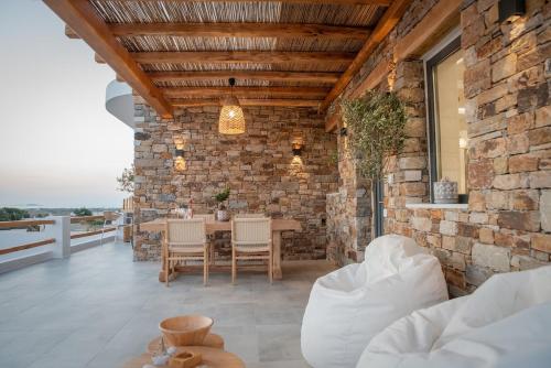 a stone walled patio with a table and chairs at Stone Waves Αpartments in Agios Arsenios