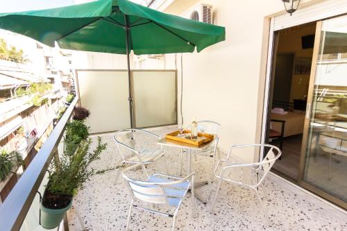 a table and chairs with a green umbrella on a patio at Zappion Hotel in Athens