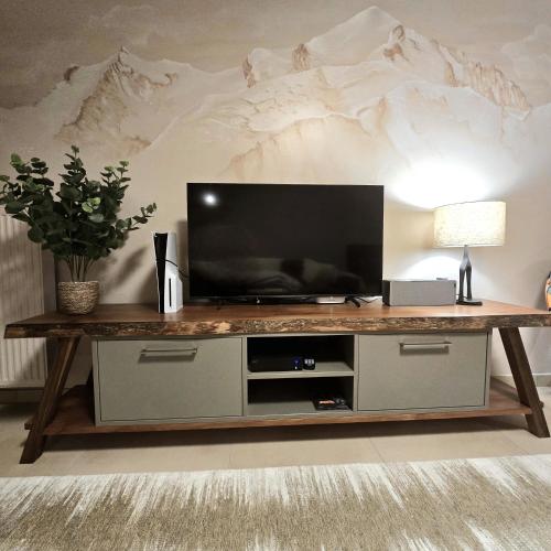 a living room with a television on a wooden table at Le Miroir De Saint-Jacques in Sallanches