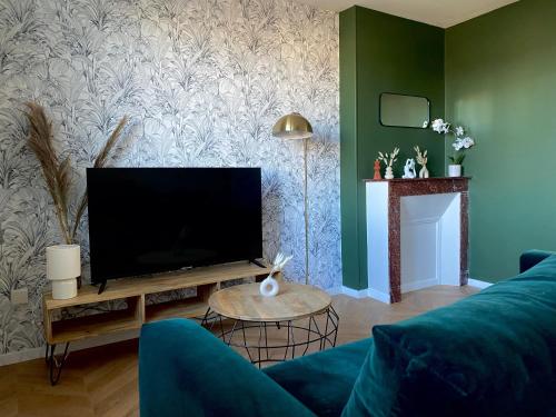 a living room with a blue couch and a flat screen tv at L'écrin vert - Wifi - Netflix - Climatisation - Parking Gratuit in Périgueux
