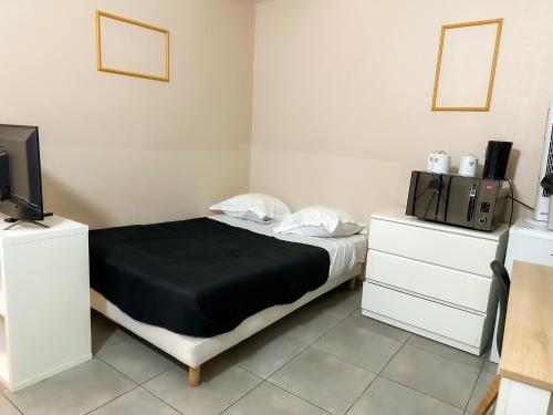a bedroom with a bed and two dressers and a television at Studio SN4 - Centre-Ville Meaux - Proche Disneyland in Meaux