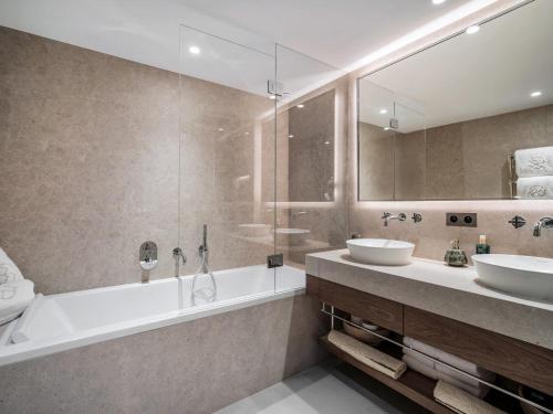 une salle de bain avec deux lavabos, une baignoire et un miroir dans l'établissement Chalet d'exception avec sauna, piscine chauffée et salle de cinéma - FR-1-570-64, à Saint-Martin-de-Belleville