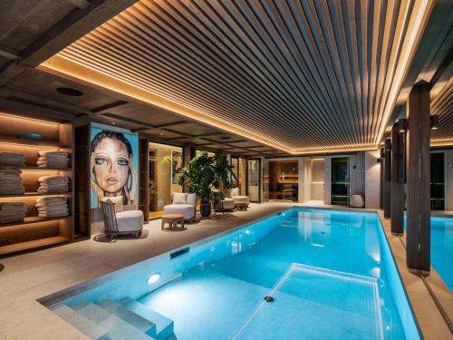 une piscine dans une maison avec un tableau représentant une femme dans l'établissement Chalet d'exception avec sauna, piscine chauffée et salle de cinéma - FR-1-570-64, à Saint-Martin-de-Belleville