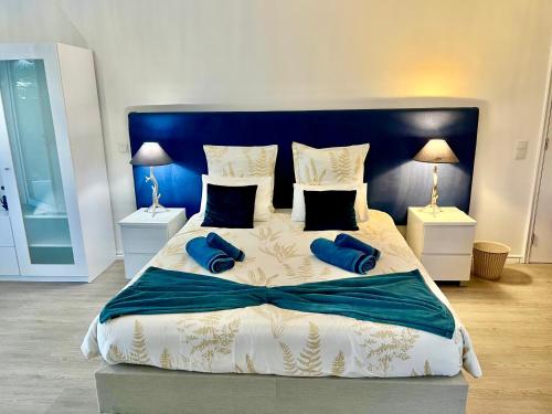 a bedroom with a large bed with two blue pillows at Casa Caloura Ocean Deluxe Accommodation & Spa in Lagoa