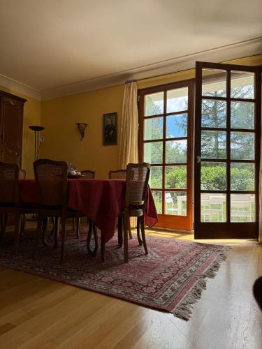une salle à manger avec une table, des chaises et des fenêtres dans l'établissement Grande maison avec jardin et son accès privé à la rivière Drôme, à Mirabel-et-Blacons