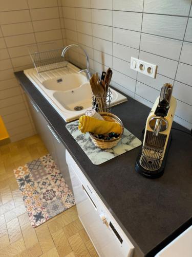 - un comptoir de cuisine avec évier et un panier d'ustensiles dans l'établissement Grande maison avec jardin et son accès privé à la rivière Drôme, à Mirabel-et-Blacons