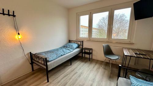 a room with a bed and a desk and two windows at MiCasa TuCasa - 3-R Apartment Leipziger Neuseenland Nova in Kitzscher