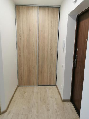 an empty room with a wooden door and a hallway at Ragaines apartamentai self check-in in Klaipėda