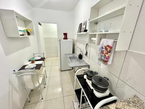 a kitchen with white cabinets and a table and a refrigerator at Lindo APT 05 em bairro central de Petrolina em prédio familiar in Petrolina