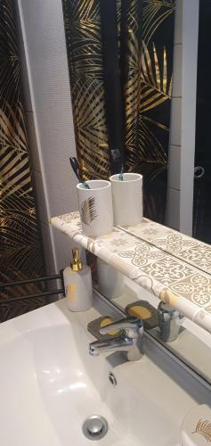 - un lavabo avec 2 tasses sur un miroir dans l'établissement Studio cosy 33, à Bassens