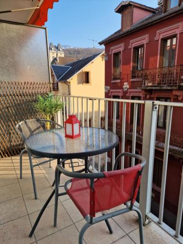une table et deux chaises sur un balcon dans l'établissement L'Aixotique, à Aix-les-Bains