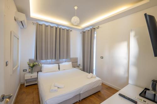 a bedroom with a white bed and a desk at Hotel Myrtai - City Center in Sarandë