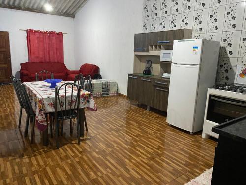 a kitchen with a table and a white refrigerator at Casa de aluguel da vitoria in Ubatuba