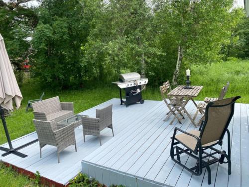 a wooden deck with chairs and a grill and a table at cozy cottage 5 min walk from Parlee beach in Pointe-du-Chêne