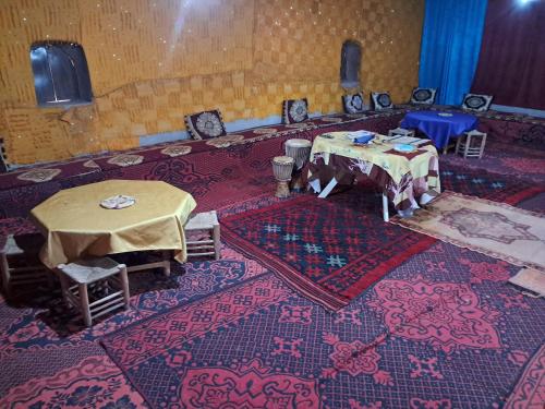 a room with two tables and chairs on a rug at Camp Sahara inspiration in Mhamid