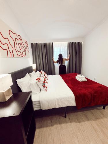 a woman is looking out the window of a bedroom at Gardens Guest House-Hostel in São Vicente
