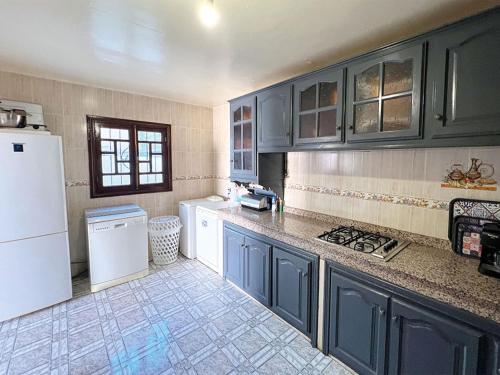 a kitchen with blue cabinets and a white refrigerator at Maison de Vacances Idéale à 10 min de l'Aéroport in Marrakech
