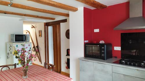 a kitchen with a table with a red wall at Gite sur le Mont in Lapoutroie