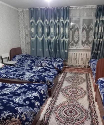 a bedroom with two beds and a rug at Kausar guest house in Karabulak