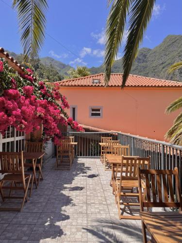 a patio with tables and chairs and pink flowers at Gardens Guest House-Hostel in São Vicente