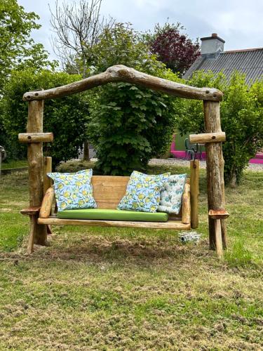 a wooden bench with pillows sitting in a yard at Lemonade Cottages in Kilrush