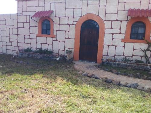a building with a door and two windows at LA HUERTA Cabaña y Hospedaje in Huasca de Ocampo