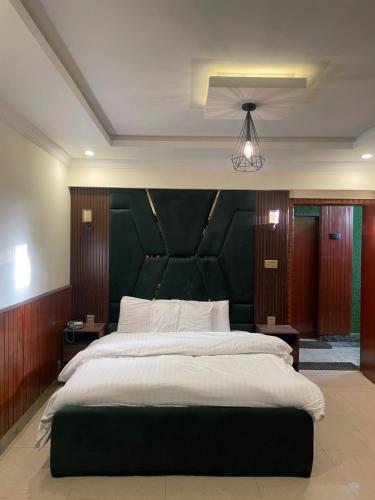 a bedroom with a large bed with a green headboard at Mussiaree Hotel in Murree