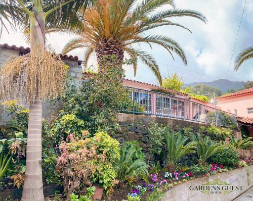 a palm tree and flowers in front of a building at Gardens Guest House-Hostel in São Vicente