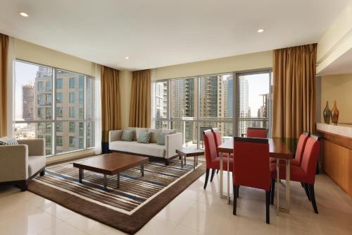 a living room with a table and chairs and large windows at Ramada by Wyndham Downtown Dubai in Dubai