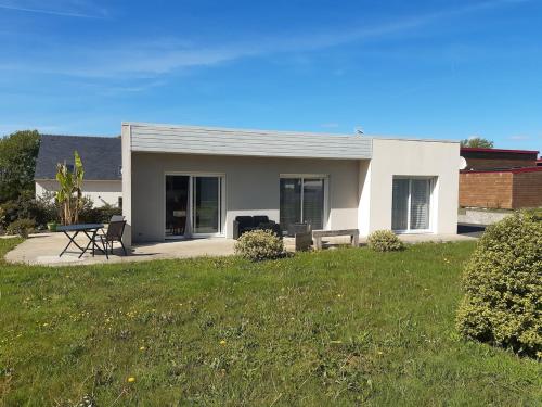 a white house with a picnic table and chairs in a yard at La route des Genêts in Locronan