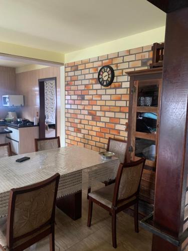 una cucina con un tavolo e sedie e un orologio su un muro di mattoni di Casa família com piscina a Garopaba