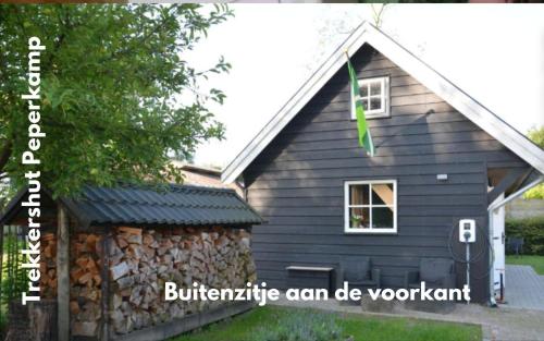 a black house with a stone wall at landelijke trekkershut in Zelhem