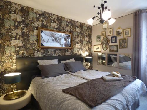 - une chambre avec un grand lit et un mur recouvert de papier peint dans l'établissement L'Instant pour Soi, à Saint-Gervais-les-Trois-Clochers