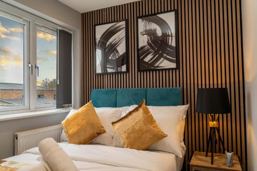 a bedroom with a bed with a blue headboard and two windows at Central Oxford Apartments Terrace in Oxford