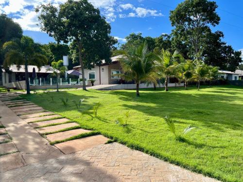 Un patio con césped, palmeras y una casa. en Area de Lazer fazenda Papuã- Lugar de PAZ, en Caldas Novas