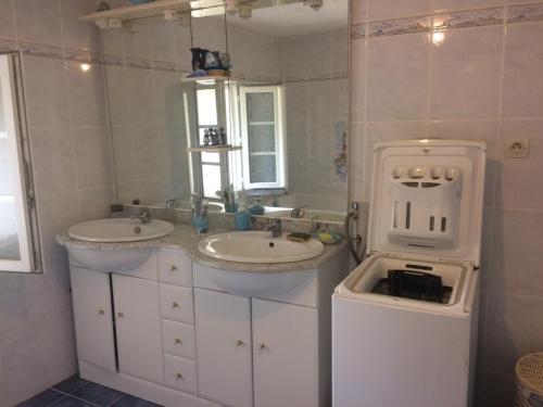 un bagno con due lavandini e un grande specchio di Maison familiale a Médis