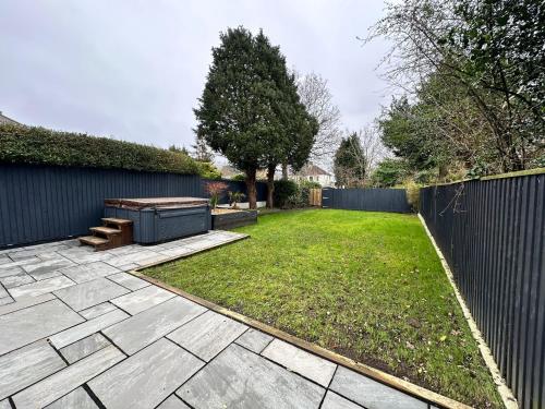 a backyard with a fence and a lawn with a grill at Escape to the Beach in Poole